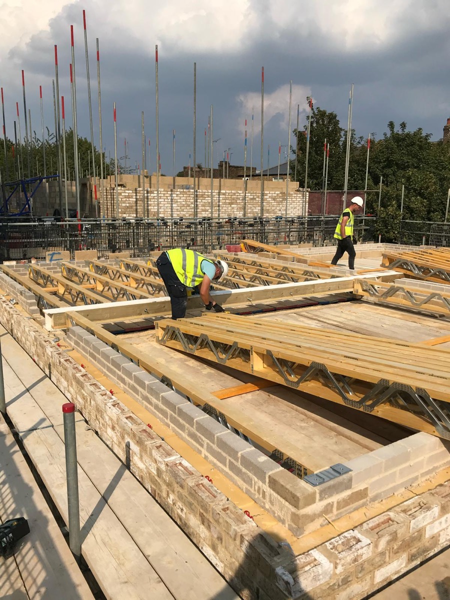 Carpenter installing engineered timber floor joists on a new-build